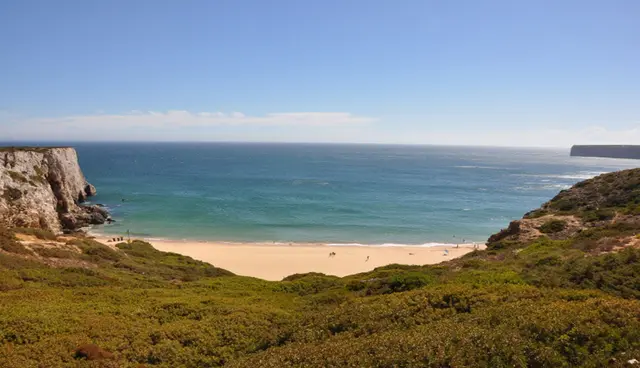A sandy beach below green clifftops on the south-west coast
