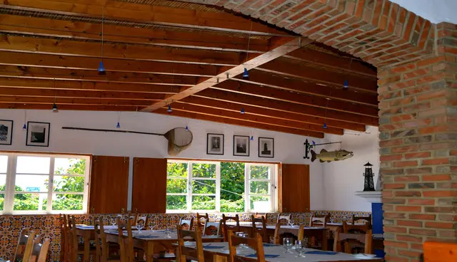 The restaurant dining room with wooden beams, brick arches and set tables