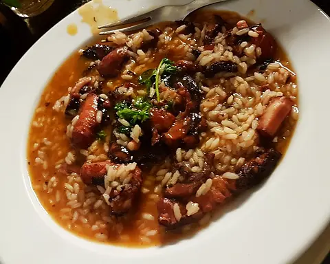 Octopus rice with fresh coriander on a white plate