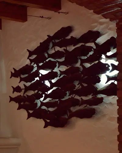 A school of dark metal fish mounted on a white dining-room wall